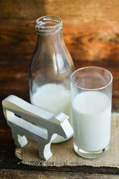 milk bottle, glass of milk, a figure of a cow the concept of a village power, farm-fresh products on a natural wooden background