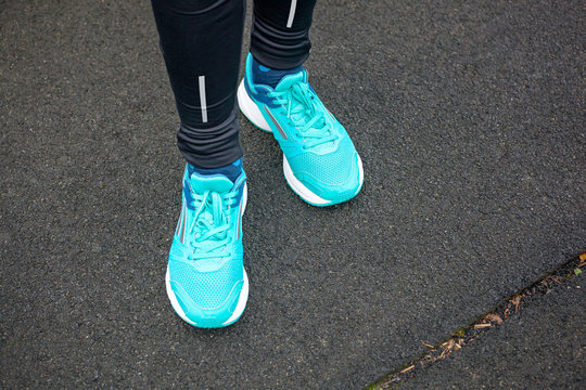 Close up of legs in running shoes standing on asphalt.