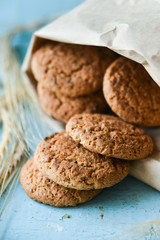 fresh oatmeal cookies in a bag made of paper on wooden background