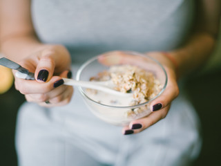female hands with a spoon of granola