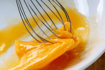 whisking the eggs with a whisk. White background. Macro