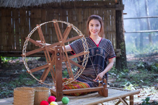 Beautiful Thai women smile in karen suit spinning thread on a bamboo mat in a forest nature local village Thailand