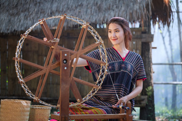 Beautiful Thai women smile in karen suit spinning thread on a bamboo mat in a forest nature local...