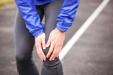 Cropped shot of a young runner holding his injured knee while running.