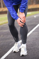 Cropped shot of a young runner holding his injured knee while running.