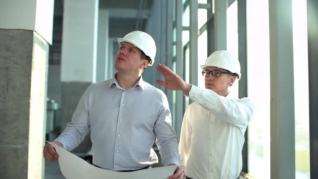 Portrait of  businessman on construction site with foreman. Man architect engineer checks industrial air ducts. engineers architects in hard hat working, discussing, checking site with blueprint plan