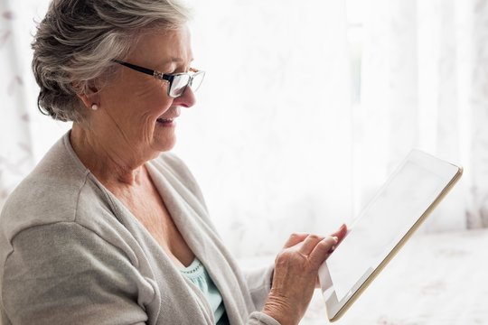 Smiling senior woman using digital tablet at home