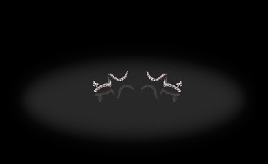 Platinum precious earrings horns with diamonds on black background.