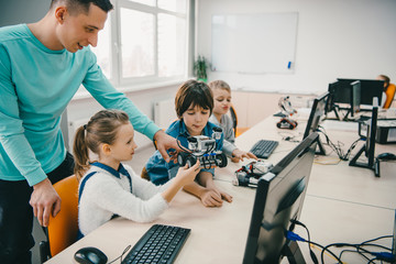 teacher helping his teen students with diy robot on stem education class