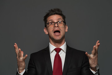 Disheveled young man the manager in formal suit is pleased with unexpected success on gray background