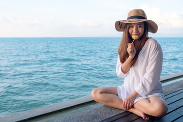 Portrait image of a happy beautiful asian woman enjoy eating pineapple by the sea with clear blue sky background