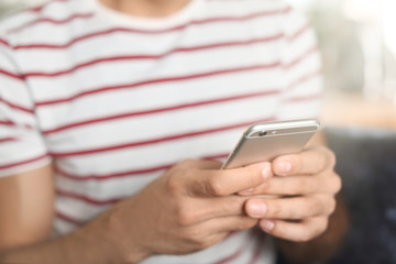 Young man using mobile phone indoors