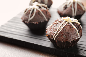 Tasty chocolate cupcakes on wooden board