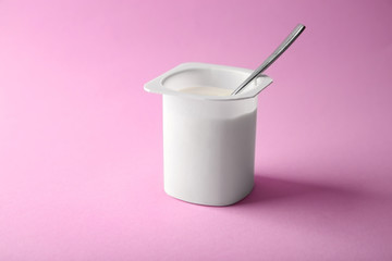 Plastic cup with yummy yogurt on color background