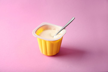 Plastic cup with yummy yogurt on color background