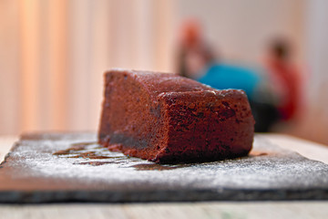 Piece of sweet chocolate pie on black cutting board.