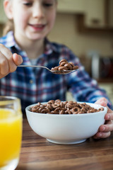 Girl Eating Bowl Of Sugary Breakfast Cereal In Kitchen