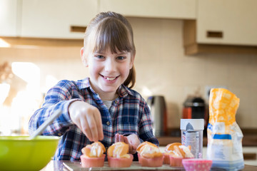 Portrait Of Girl In Kitchen Decorating Home Made Cupcakes