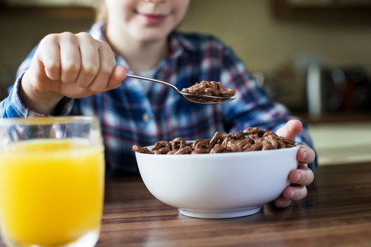 Close Up Of Girl Eating Bowl Of Sugary Breakfast Cereal In Kitchen