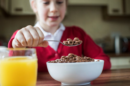 Girl Wearing School Uniform Eating Bowl Of Sugary Breakfast Cereal In Kitchen