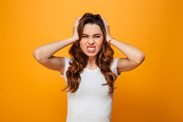 Fototapeta premium Displeased serious brunette woman in t-shirt holding her head