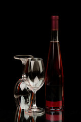 Vine Bottle of drink and two glasses on black background with mirrored reflection
