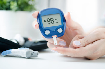 Woman checking blood sugar level by glucometer