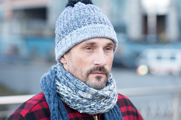 Close up of white male in city. Portrait of white guy on street. Bearded man in winter hat and red jacket