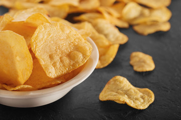 Pile of crispy potato chips lying  on an old concrete table in kitchen. Concept of fast food background. Free place for text.