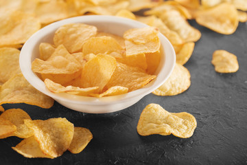 Pile of crispy potato chips lying  on an old concrete table in kitchen. Concept of fast food background. Free place for text.