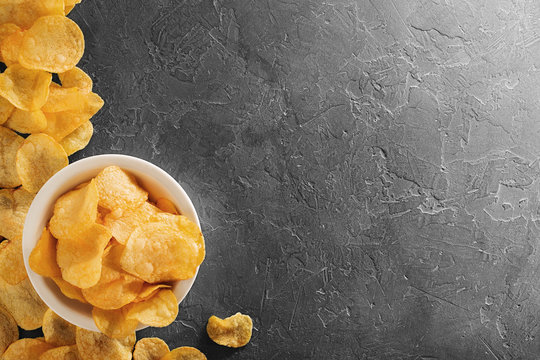 Pile of crispy potato chips lying  on an old concrete table in kitchen. Concept of fast food background. Free place for text, top view.