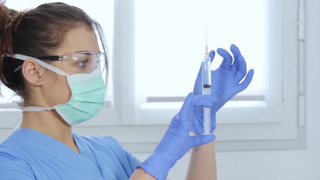 young nurse preparing injection with syringe in hospital