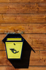 Yellow metal mailbox on a wooden wall