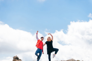 Couple of lovers dancing at top of mountain on massive clouds background. Happy pair in love celebrating success after reaching and conquering highest peak. Man and woman enjoying nature outdoor.