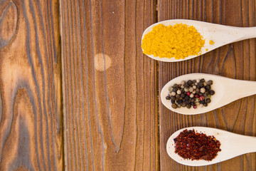 Obraz na płótnie Canvas Plastic spoons with dry spices and fresh herbs on a wooden rough boards background, top view, close up