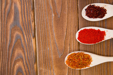 Plastic spoons with dry spices and fresh herbs on a wooden rough boards background, top view, close up