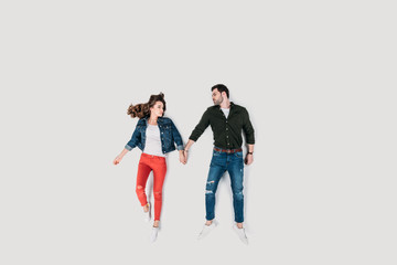 Naklejka premium top view of stylish happy couple holding hands isolated on white