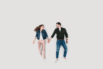 Fototapeta premium top view of stylish young couple holding hands isolated on white