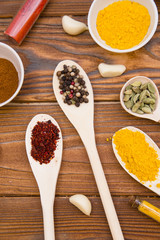 Plastic spoons and cups with dry spices and fresh herbs on a wooden rough boards background, top view, close up