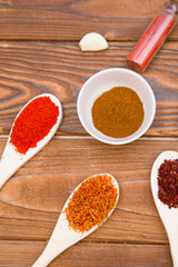 Plastic spoons and cups with dry spices and fresh herbs on a wooden rough boards background, top view, close up
