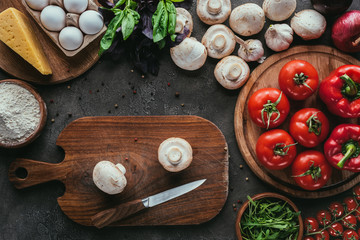 top view of different raw ingredients for pizza and knife on concrete surface