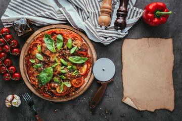 top view of delicious pizza with cutter and blank paper on concrete table