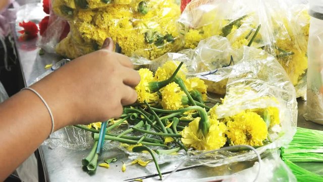 close up of a florist preparing flowers for a wreath at sri maha mariamman temple in bangkok, thailand