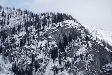 Granite mountains covered with snow and winter forest near Mont Blanc Alpes, Italy
