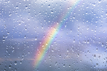 Rainbow through a window with drops after storm