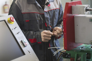 Electrician on overalls is working with energy panel and machinery equipment on plant