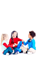Three diverse elementary students sitting on floor and playing rock paper scissors game