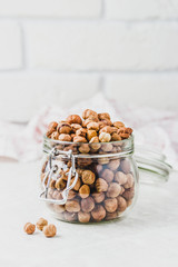 Hazelnuts in a glass jar on white background. Selective focus, copy space.