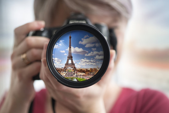 Eiffel tower reflection in camera lens with blurred woman face.