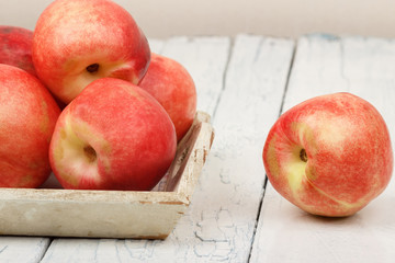 Ripe red peaches in the tray on the white wooden table